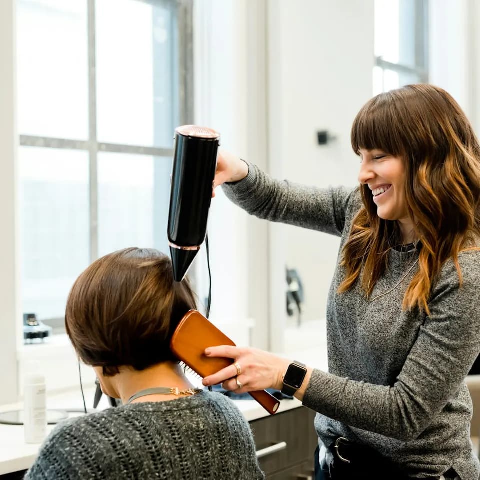 A stylist blow-drying a client's hair in a salon